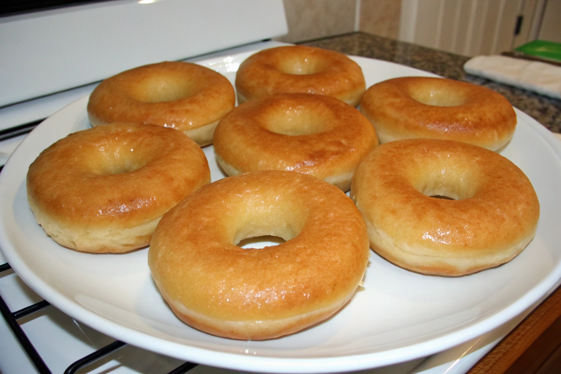 Freshly fried plain donuts with a golden-brown crust, lightly dusted with powdered sugar.